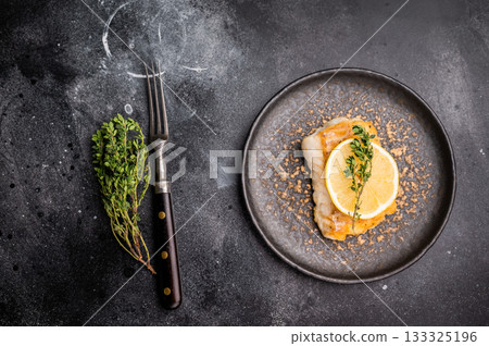Roast Halibut fish loin fiilet on plate. Black background. top view 133325196