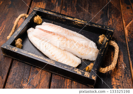 Fresh fish meat, Raw cod loin pieces without skin in wooden tray. wooden background. top view Fresh fish meat, Raw cod loin pieces without skin in wooden tray. wooden background. top view 133325198