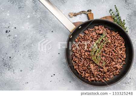 Frying Pan with fried mince beef meat, fresh cooked forcemeat. grey background. top view Frying Pan with fried mince beef meat, fresh cooked forcemeat. grey background. top view 133325248