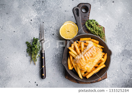 Fish and chips with roast white fish fillet and French fry in skillet. grey background. top view 133325284
