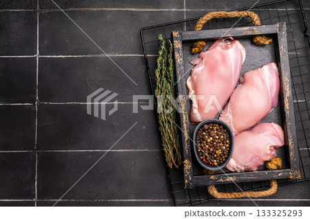 Raw Chicken thighs fillets in a wooden tray. black background. top view 133325293