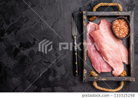 Raw pork chop fillet steaks in a wooden tray. black background. top view 133325298