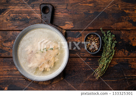 Bowl of clear chicken broth with meat. wooden background. top view Bowl of clear chicken broth with meat. wooden background. top view 133325301