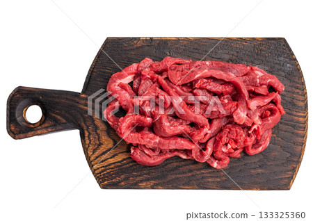 Uncooked Raw beef sliced meat, strips for cooking beef stroganoff on wooden board isolated on white background 133325360