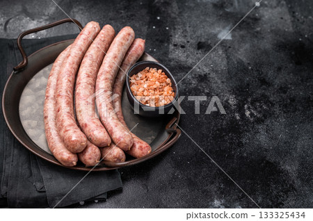 Close up of uncooked raw sausage showcasing its juicy texture, ideal for flavorful dishes and culinary creativity. black background. top view Close up of uncooked raw sausage showcasing its juicy texture, ideal for flavorful dishes and culinary creativity. black background. top view 133325434
