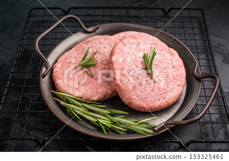 Freshly formed raw meat patty with herbs for burgers, perfect for grilling or frying to satisfy your cravings. black background. top view Freshly formed raw meat patty with herbs for burgers, perfect for grilling or frying to satisfy your cravings. black background. top view 133325461