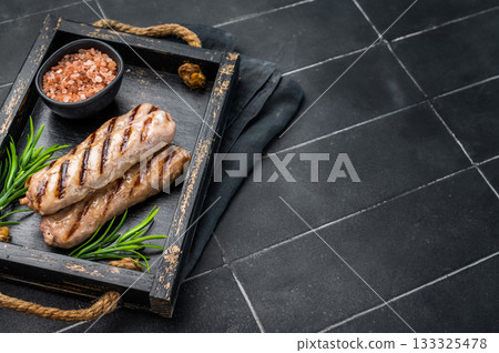 Roasted on BBQ beef and lamb sausages in wooden tray. black background. top view Roasted on BBQ beef and lamb sausages in wooden tray. black background. top view 133325478