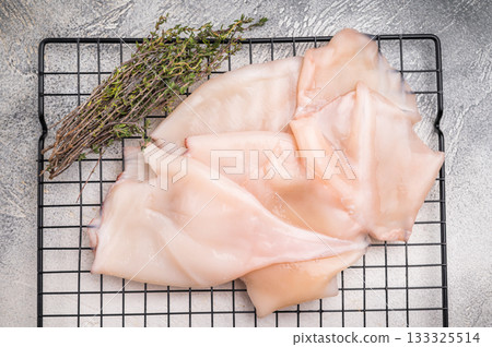 Close up of tender raw squid showcasing its smooth texture, ideal for culinary creativity and seafood lovers. grey background. top view Close up of tender raw squid showcasing its smooth texture, ideal for culinary creativity and seafood lovers. grey background. top view 133325514