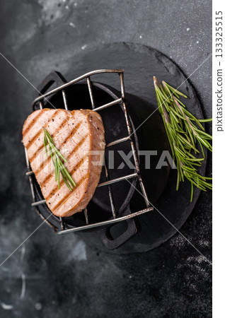 Juicy grilled tuna steak, perfectly seared with a smoky flavor, ideal for seafood lovers and gourmet dishes. black background. top view 133325515