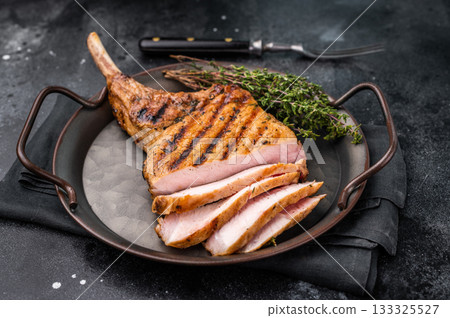 Flavorful grilled pork loin chop with bone, expertly cooked to perfection, making it the star of any meal. black background. top view Flavorful grilled pork loin chop with bone, expertly cooked to perfection, making it the star of any meal. black background. top view 133325527