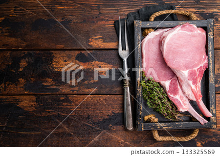 Uncooked Tomahawk pork chop steak, ready to be seasoned and cooked to perfection for a mouthwatering meal. wooden background. top view Uncooked Tomahawk pork chop steak, ready to be seasoned and cooked to perfection for a mouthwatering meal. wooden background. top view 133325569