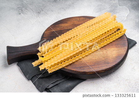 Delicate raw mafaldine pasta noodles, perfect for tossing with fresh ingredients and savory sauces. white background. top view 133325611