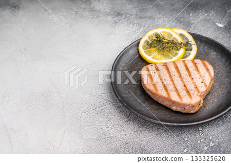 Deliciously charred grilled tuna steak, served with fresh herbs, a healthy and flavorful choice for any meal. white background. top view 133325620