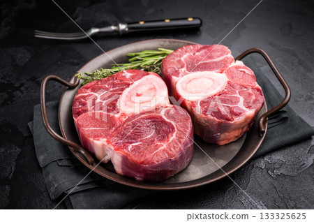 Freshly cross cut shank osso buco, ossobuco meat featuring succulent meat and bone marrow, waiting to elevate your cooking experience. black background. top view Freshly cross cut shank osso buco, ossobuco meat featuring succulent meat and bone marrow, waiting to elevate your cooking experience. black background. top view 133325625