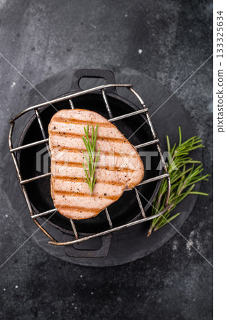 Juicy grilled tuna steak, perfectly seared with a smoky flavor, ideal for seafood lovers and gourmet dishes. black background. top view 133325634