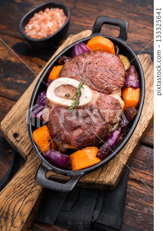 Hearty ossobuco slow cooked to perfection, showcasing succulent osso buco shank meat and aromatic herbs in a comforting stew. wooden background. top view 133325641