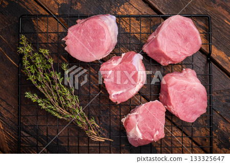 Uncooked pork loin medallion, cut tenderloin ready to be seasoned and cooked into a delicious gourmet dish. wooden background. top view Uncooked pork loin medallion, cut tenderloin ready to be seasoned and cooked into a delicious gourmet dish. wooden background. top view 133325647
