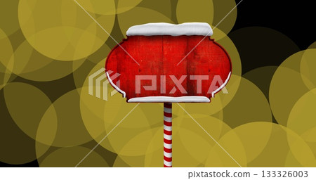 Displaying blank red wooden sign with snow trim on striped pole in festive display, golden lights 133326003