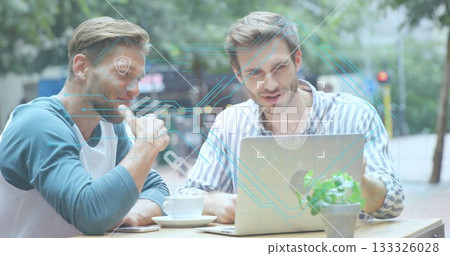 Collaborating colleagues pointing at laptop in street cafe, with coffee cups and security overlay 133326028