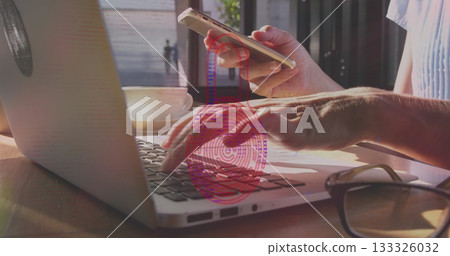 Typing hands on silver laptop at cafe table, with gold smartphone, coffee cup, red fingerprint 133326032
