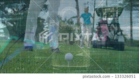 Addressing golfer lining up golf ball on tee with club on fairway, golf cart with bags 133326051
