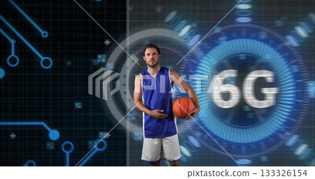 Posing adult male athlete in jersey holding basketball in tech studio, with holographic 6G overlay Posing adult male athlete in jersey holding basketball in tech studio, with holographic 6G overlay 133326154