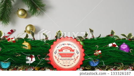 Displaying scalloped greeting badge centered on white backdrop, with fir branches and ornaments 133326187