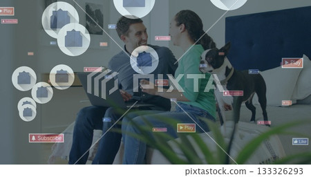 Browsing couple sitting together on bed in bedroom, with laptop and social media icon overlays Browsing couple sitting together on bed in bedroom, with laptop and social media icon overlays 133326293
