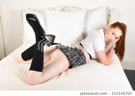 Tall, attractive, redhead model dressed as a naughty schoolgirl in a plaid skirt and white shirt, posing on her bed Tall, attractive, redhead model dressed as a naughty schoolgirl in a plaid skirt and white shirt, posing on her bed 133326703