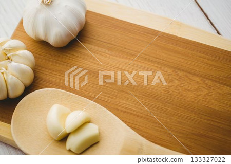 Garlic cloves and bulb on wooden chopping board 133327022