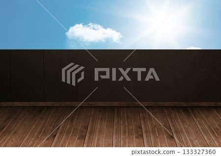 Empty wooden deck meeting dark tiled wall, bright sun shining near white cloud over blue sky Empty wooden deck meeting dark tiled wall, bright sun shining near white cloud over blue sky 133327360