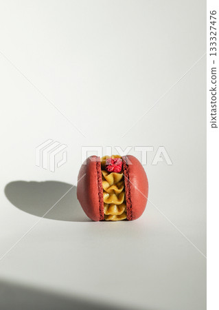 single red macaron white background shadow vertical. A solitary red macaron, potentially pistachio flavored, rests on a pure white background 133327476