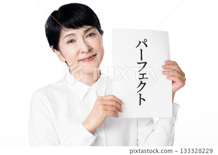 一位身穿白襯衫的老婦人面帶微笑，雙手各持一張寫著「完美」二字的紙條。 133328229