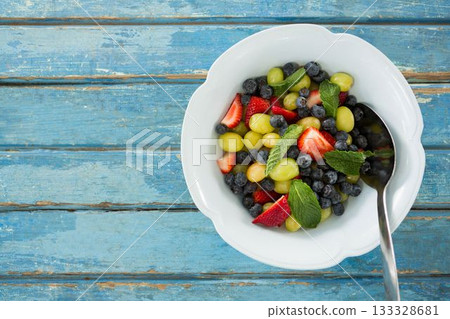 Fresh salad in bowl on blue wooden table 133328681