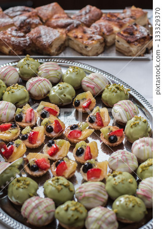Delicious pistachio and fruit tarts decorating wedding reception dessert table 133329370