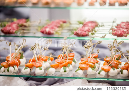 Catering preparing delicious cherry tomato and mozzarella skewers for wedding reception 133329385