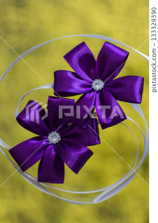 Two purple corsages with rhinestones resting on white ribbons for wedding Two purple corsages with rhinestones resting on white ribbons for wedding 133329390