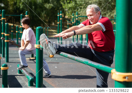 Elderly man doing leg stretching on the outdoor sports ground Elderly man doing leg stretching on the outdoor sports ground 133329822
