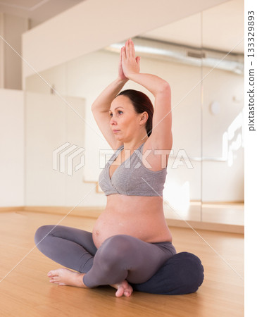 pregnant woman is engaged in yoga. Easy pose or Sukhasana. 133329893