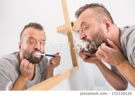 Man brushing his teeth in bathroom Man brushing his teeth in bathroom 133330226