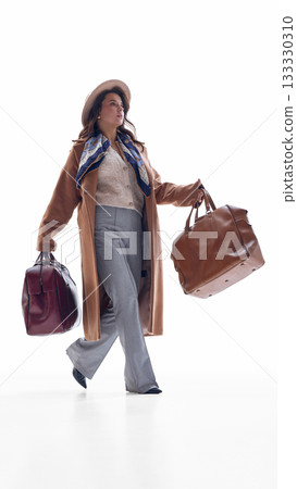 Businesswoman walking with two travel bags in confident active motion 133330310