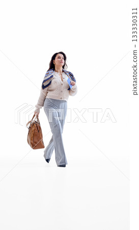 Businesswoman walking with handbag and travel ticket in determined mood Businesswoman walking with handbag and travel ticket in determined mood 133330311