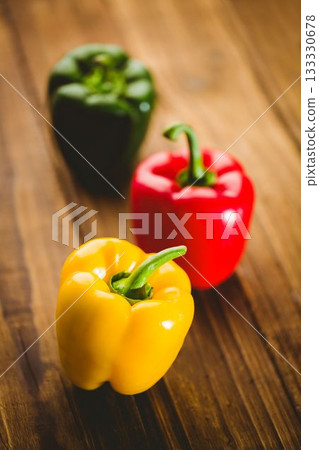 Multi colored bell peppers on wooden floor 133330678