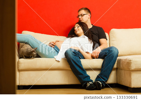 Pregnant woman and man relaxing on sofa Pregnant woman and man relaxing on sofa 133330691
