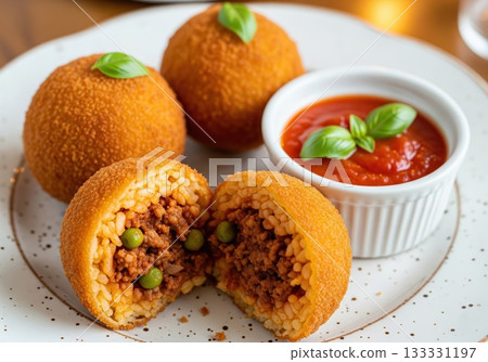Golden crispy Sicilian arancini arranged with rag+? filling beside tomato sauce highlighting authentic Mediterranean culture and flavorful homemade dish Golden crispy Sicilian arancini arranged with rag+? filling beside tomato sauce highlighting authentic Mediterranean culture and flavorful homemade dish 133331197