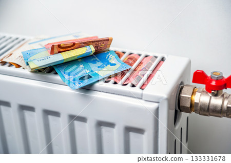 euro banknotes in a central heating radiator, the concept of expensive heating costs, closeup 133331678