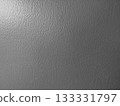 A dark gray, textured wall illuminated by natural light from the upper left 133331797