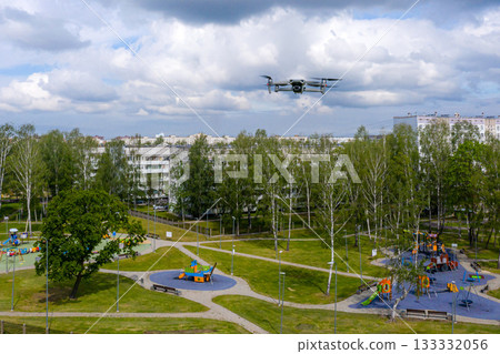flying quadcopter over the city residential area and childrens playgrounds, modern concept of order control and surveillance flying quadcopter over the city residential area and childrens playgrounds, modern concept of order control and surveillance 133332056