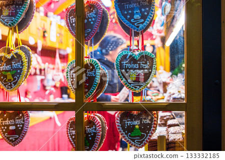 Wuerzburg, Germany, December 22th, 2024. A festive christmas market stall viewed through a window, decorated with hanging gingerbread heart cookies with colorful icing messages. 133332185
