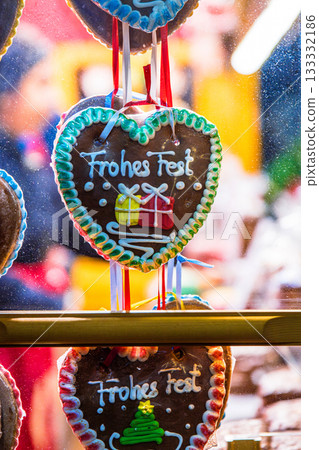 A holiday market stall packed with Frohes Fest - Happy Holidays - gingerbread hearts in a market stall window at Christmas market. Shot through the glass A holiday market stall packed with Frohes Fest - Happy Holidays - gingerbread hearts in a market stall window at Christmas market. Shot through the glass 133332186